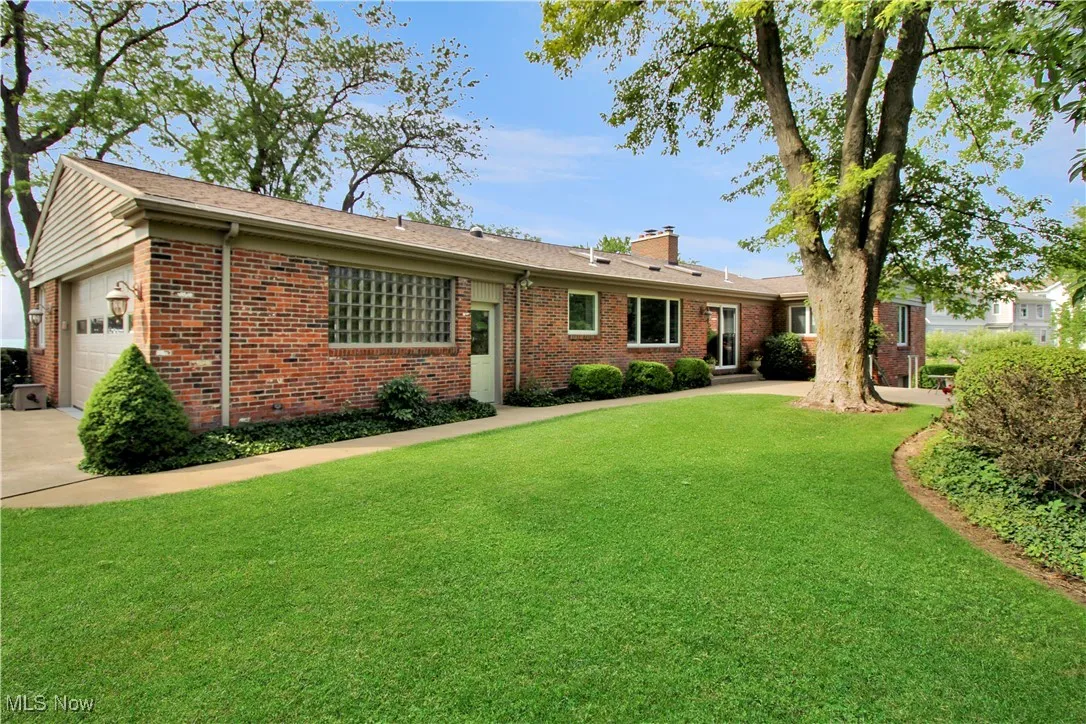 Ranch-style house featuring brick siding, a chimney, an attached garage, and a front yard