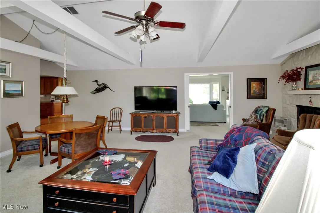 Carpeted living room with a ceiling fan and a fireplace