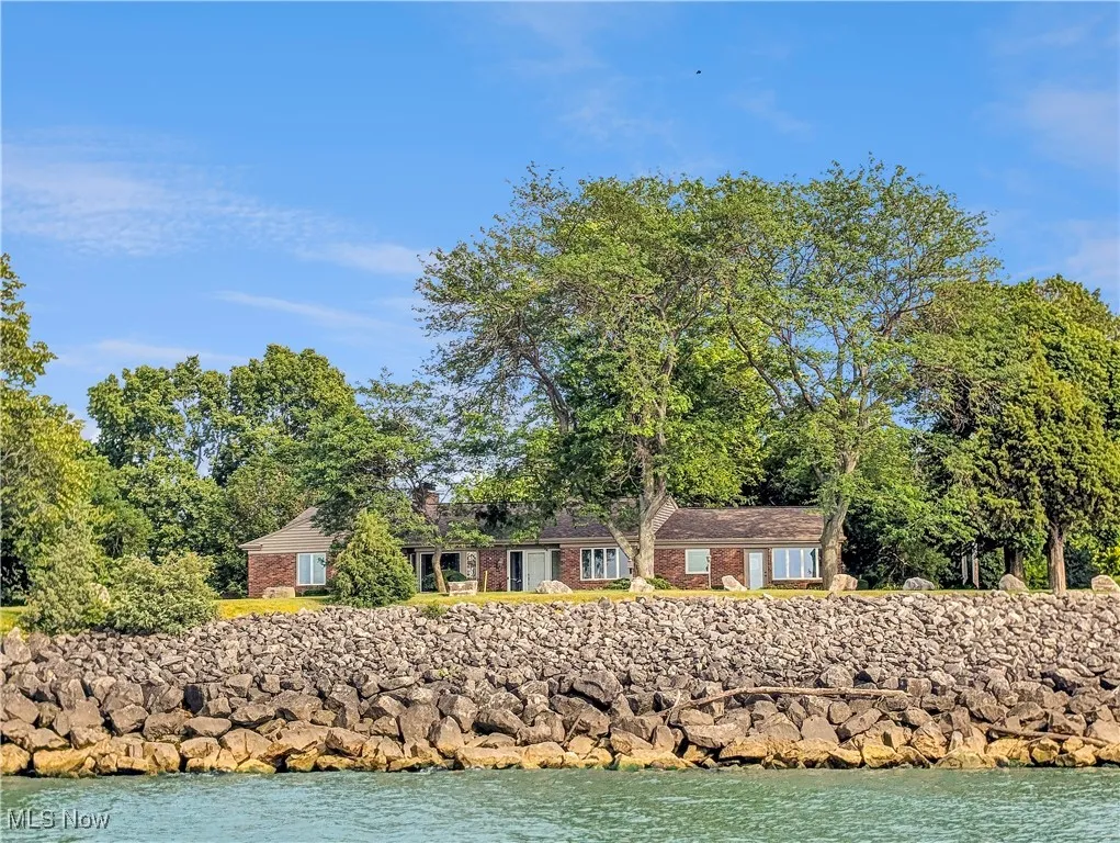 View of front of house with brick siding, a water view, and a chimney