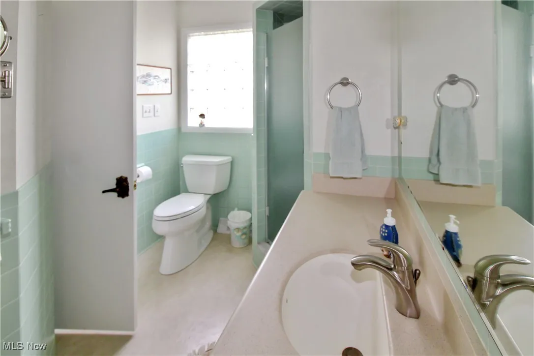 Full bath featuring tile walls, a wainscoted wall, and vanity