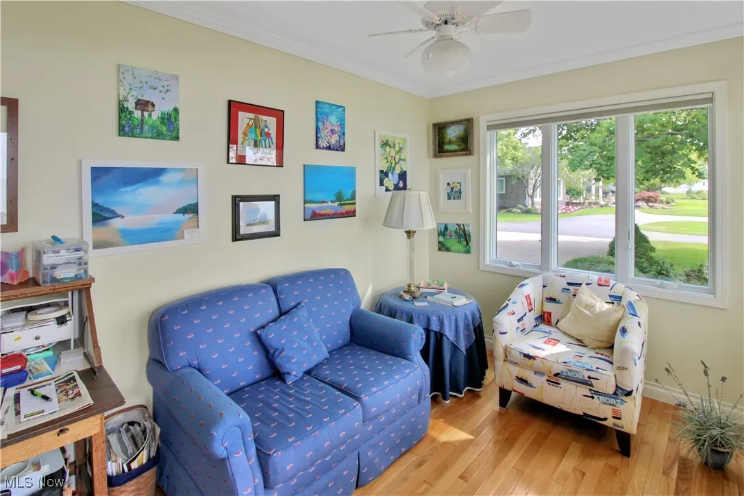 Living area featuring wood finished floors, ceiling fan, and ornamental molding