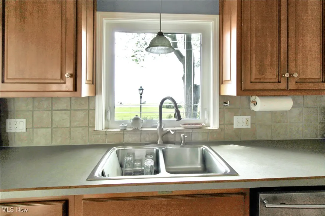 Kitchen with brown cabinetry, dishwasher, tasteful backsplash, and healthy amount of natural light