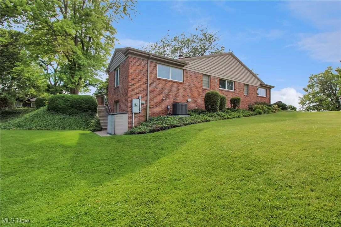 View of property exterior with an attached garage, brick siding, and a lawn