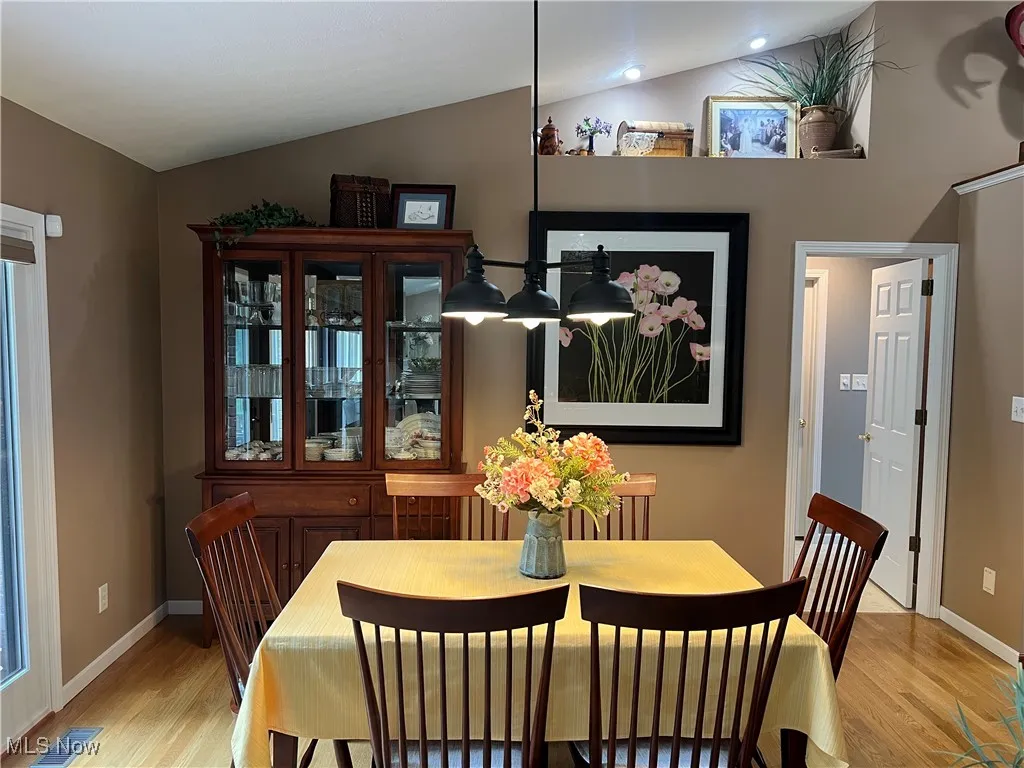 Dining area with light wood-type flooring and vaulted ceiling