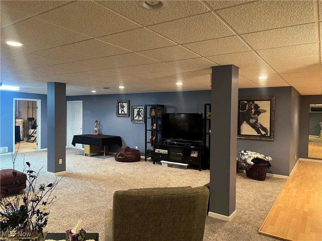 Carpeted living area featuring a drop ceiling and recessed lighting