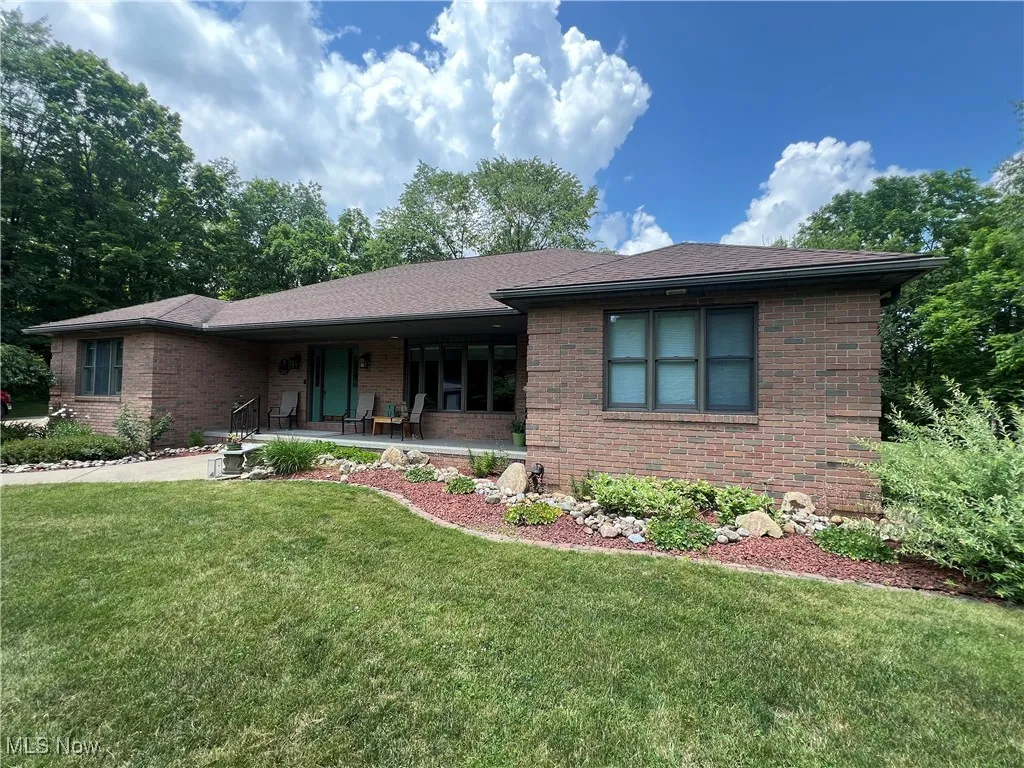 View of front of house with brick siding, a front yard, and a porch