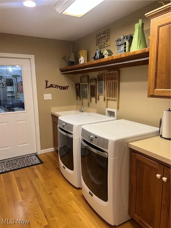 Laundry area with cabinet space, separate washer and dryer, and light wood-style flooring