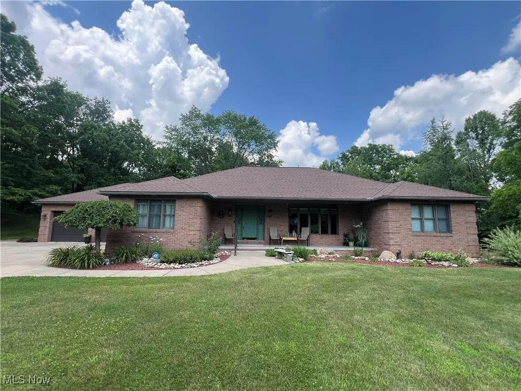 Single story home with brick siding, a porch, a front yard, an attached garage, and concrete driveway
