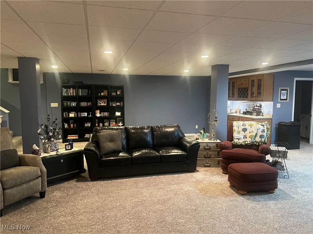 Living room featuring carpet, stairway, and a paneled ceiling