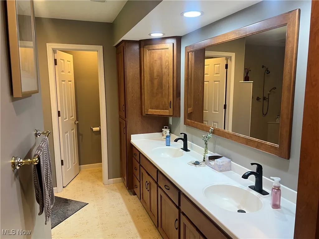 Bathroom with double vanity, a shower, and recessed lighting