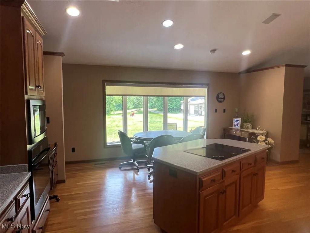 Kitchen featuring stainless steel appliances, light wood-type flooring, recessed lighting, a kitchen island, and brown cabinetry