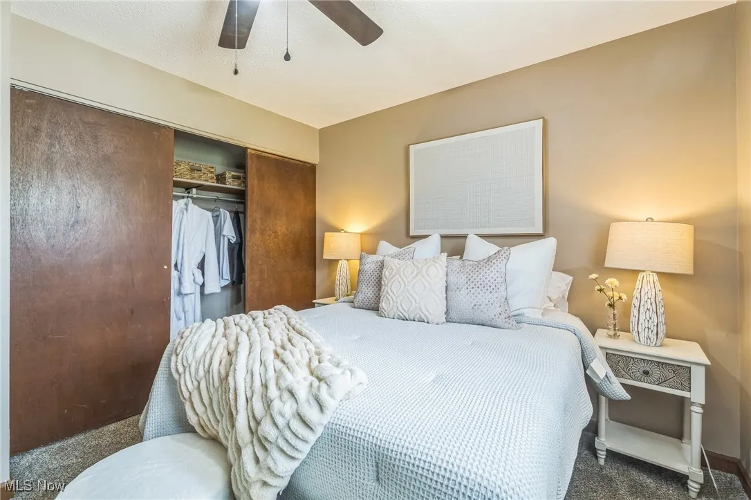Carpeted bedroom with a closet and a ceiling fan