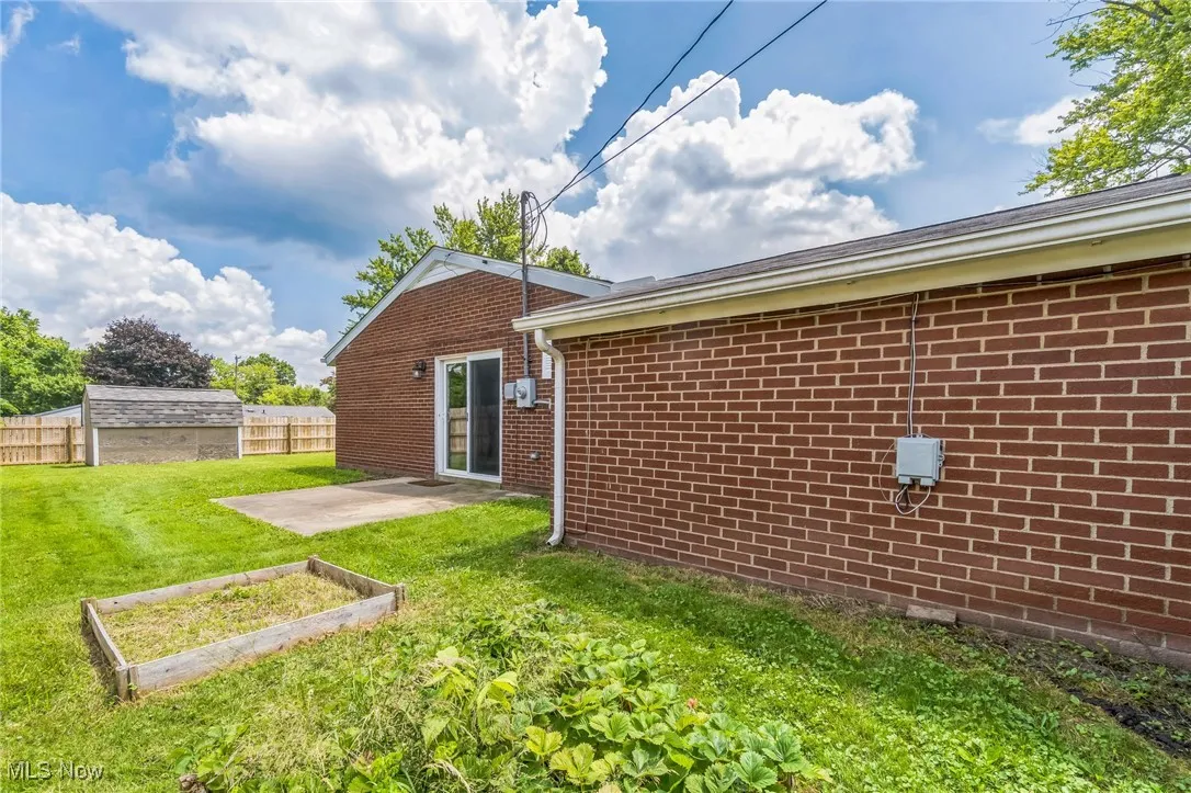 Back of house with a garden, brick siding, and a patio