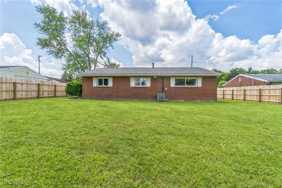 Rear view of property with a fenced backyard and brick siding