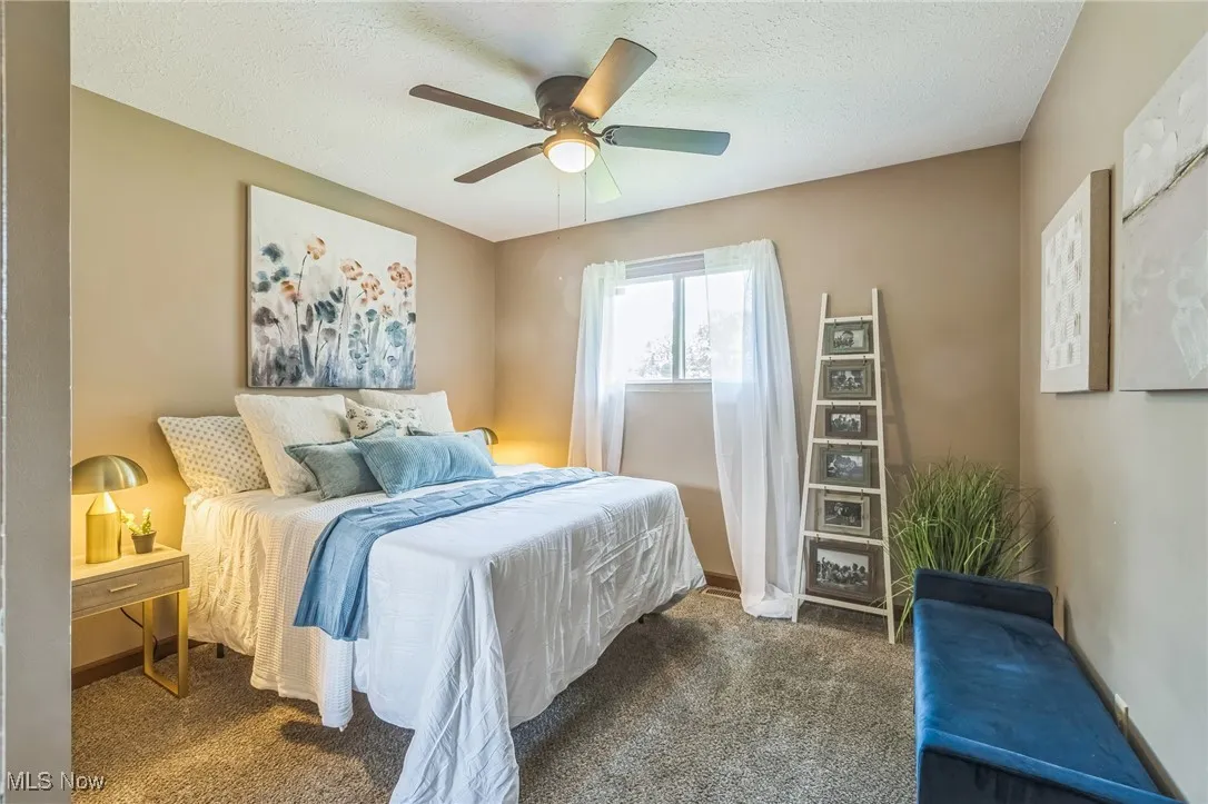 Bedroom with carpet floors, ceiling fan, and a textured ceiling