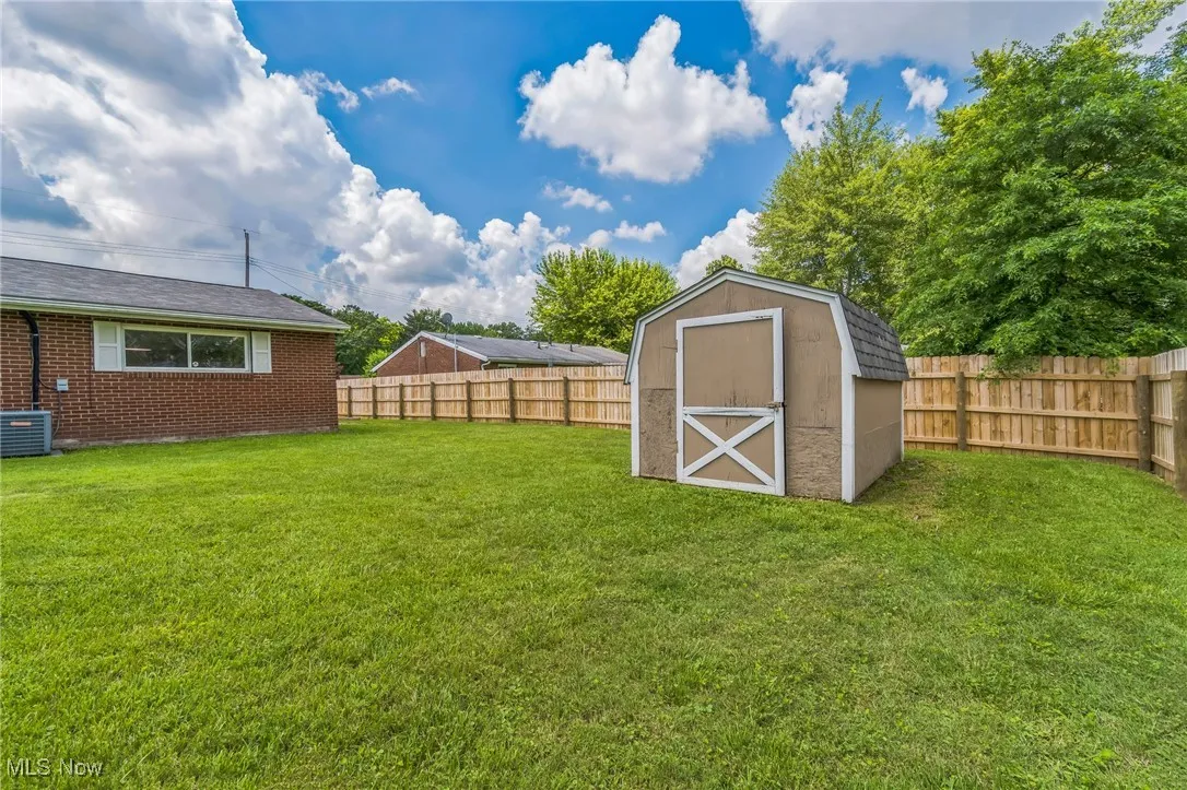 Fenced backyard featuring a shed