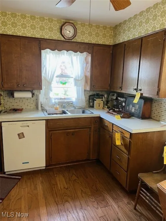 Kitchen featuring dishwasher, light countertops, backsplash, dark wood-style floors, and ceiling fan