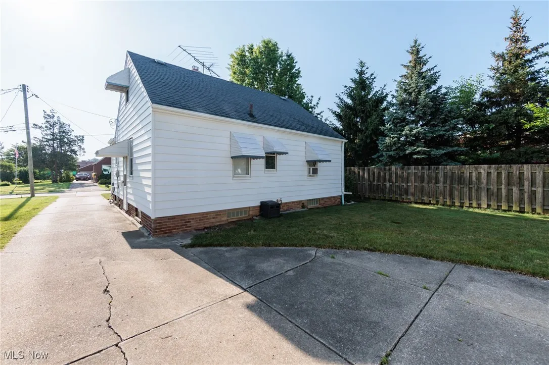 View of side of property with a shingled roof and driveway