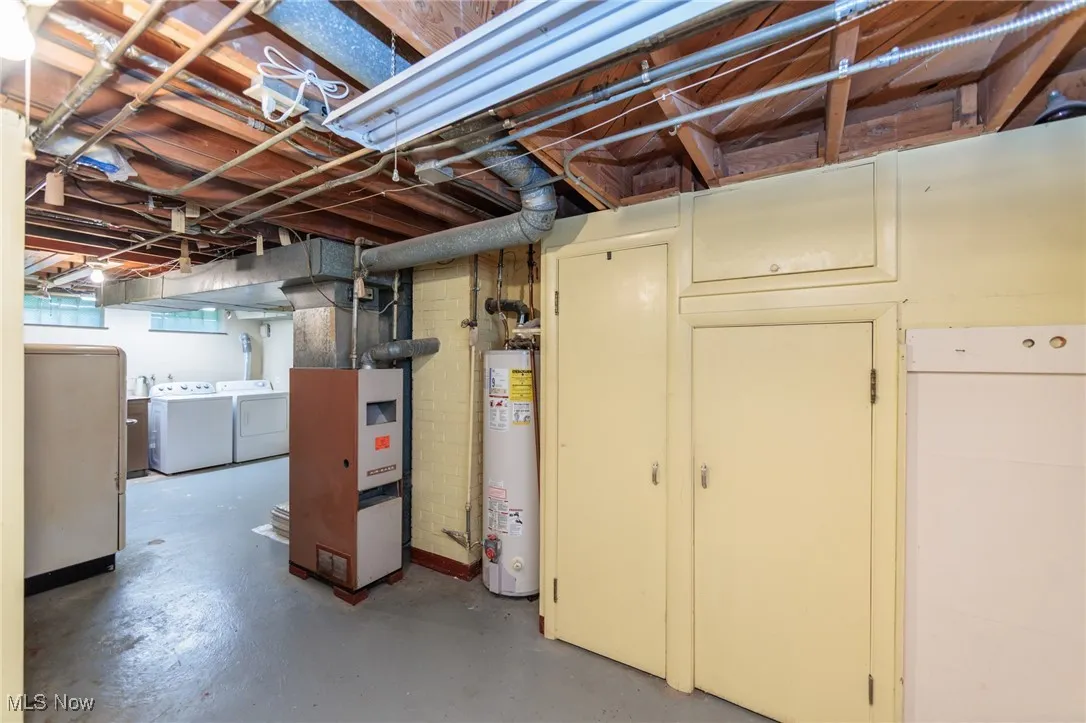 Basement featuring gas water heater, independent washer and dryer, heating unit, and fridge