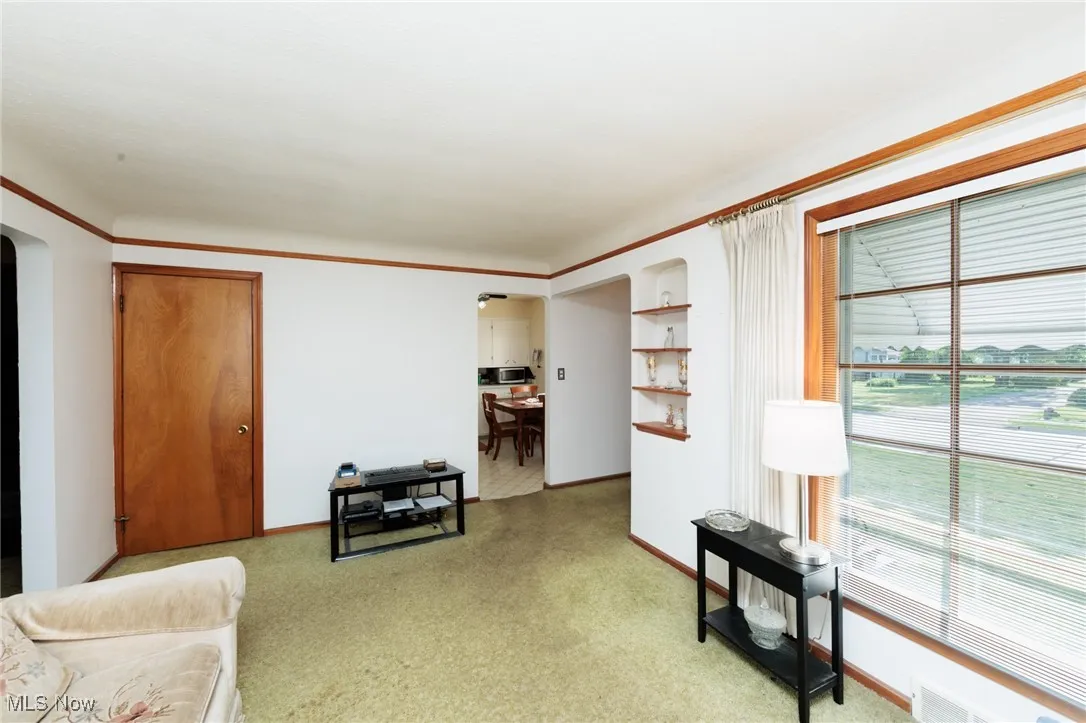 Sitting room with plenty of natural light, arched walkways, and light carpet