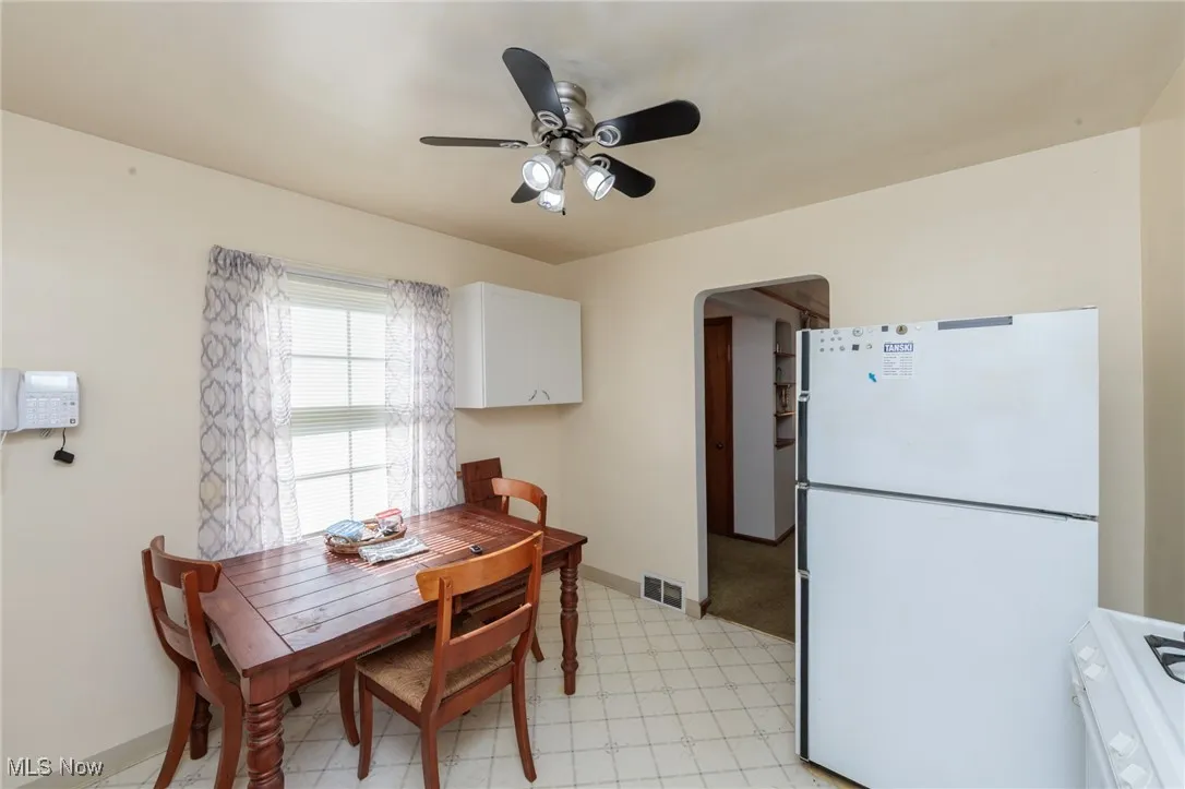 Dining room with light floors, a ceiling fan, and arched walkways