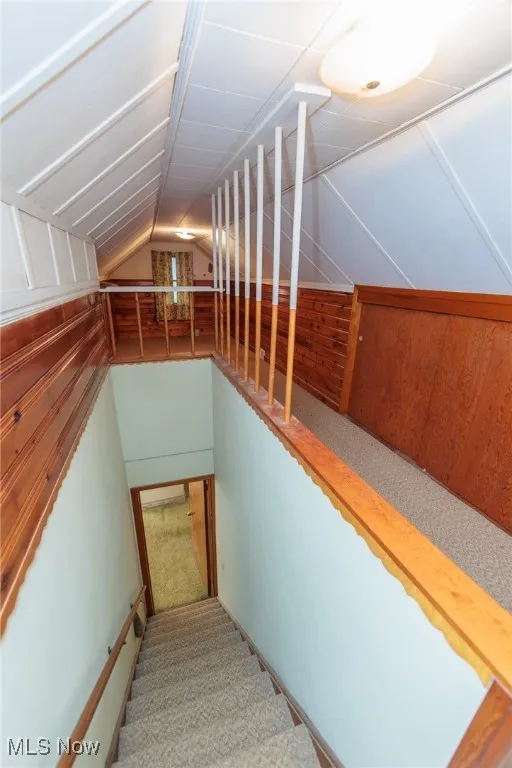 Staircase with vaulted ceiling and carpet