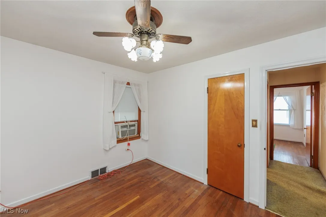 Unfurnished bedroom featuring wood finished floors, cooling unit, and a ceiling fan