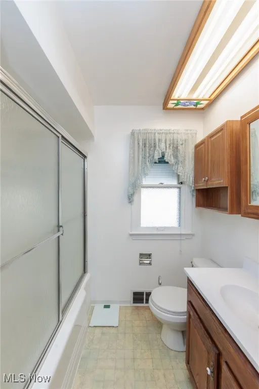 Bathroom with vanity, enclosed tub / shower combo, and tile patterned floors