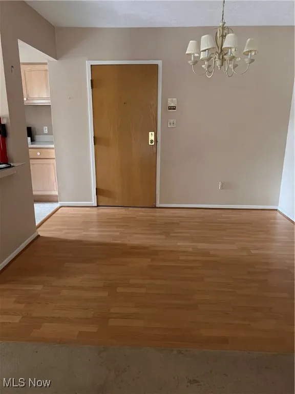 Unfurnished dining area with a chandelier and light wood-style floors