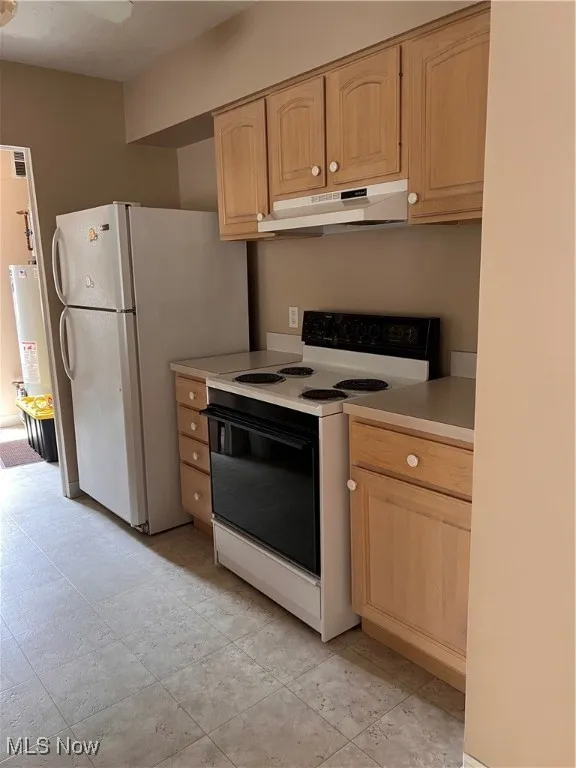 Kitchen with range with electric cooktop, range hood, light brown cabinets, light countertops, and refrigerator