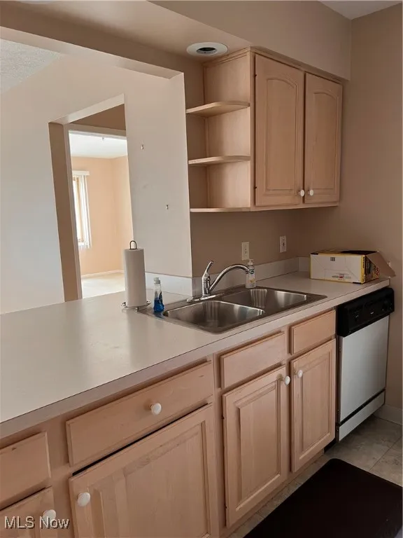 Kitchen featuring dishwasher, light brown cabinetry, light countertops, and open shelves