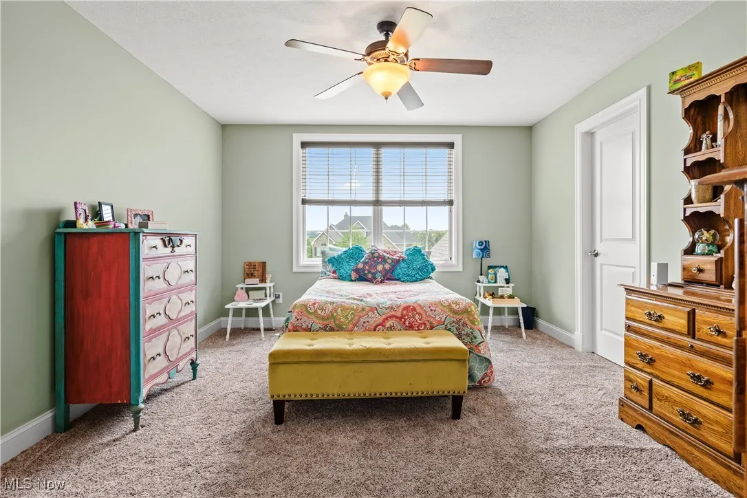 Carpeted bedroom with a ceiling fan and baseboards