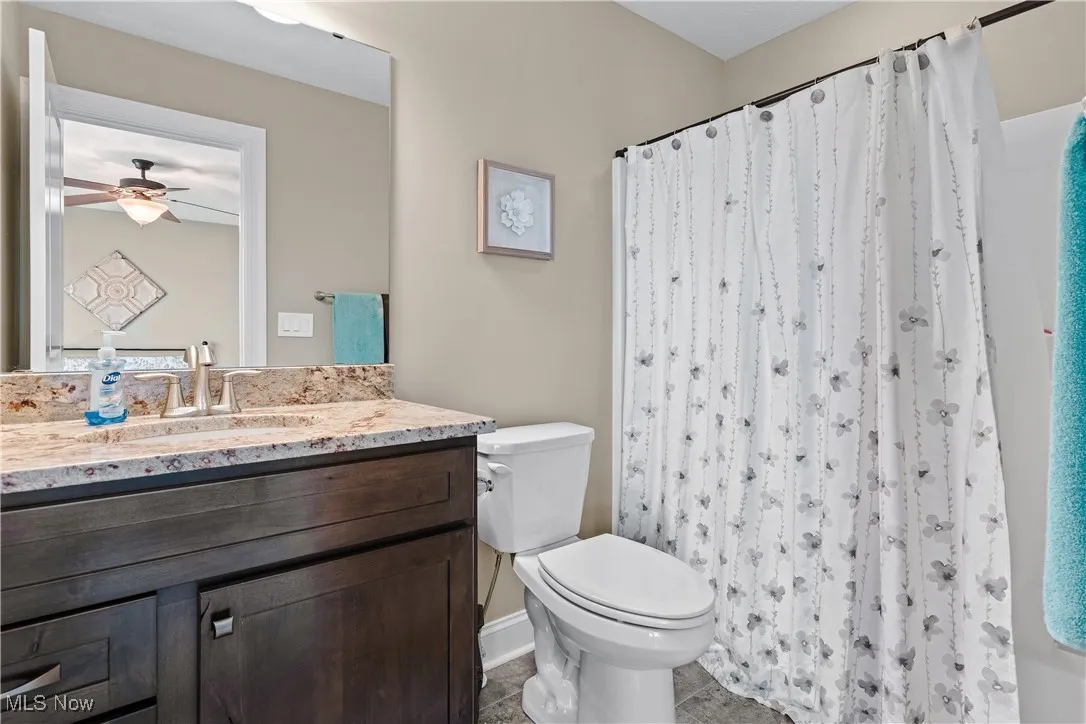 Bathroom with vanity, ceiling fan, and curtained shower