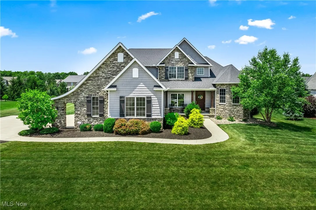 Craftsman-style house featuring stone siding, a front lawn, and roof with shingles
