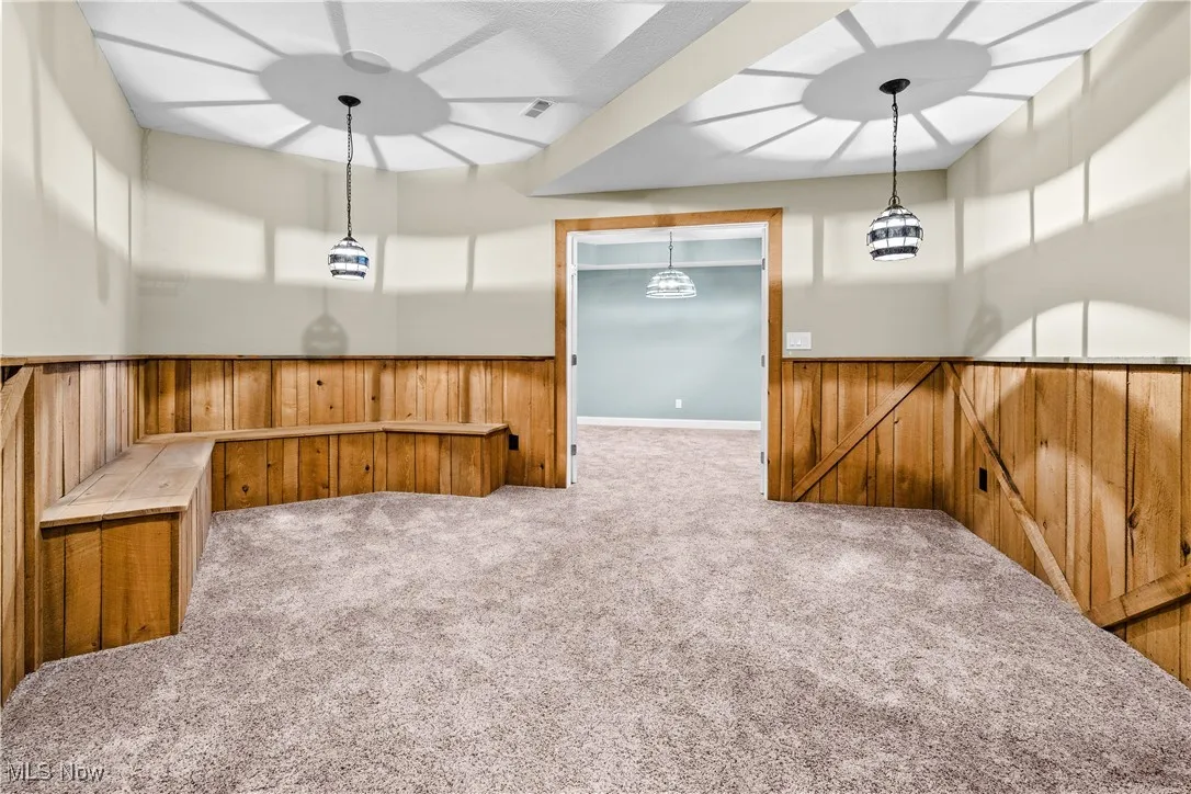 Carpeted spare room with wainscoting and wood walls