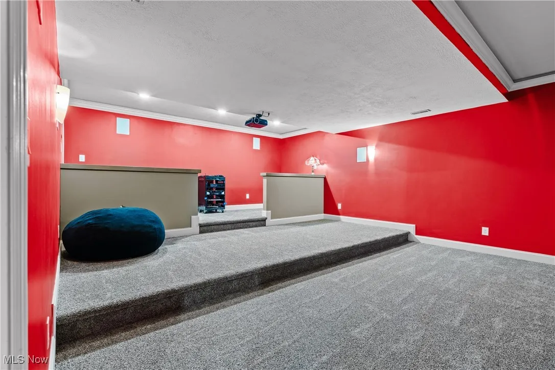 Carpeted cinema with a textured ceiling, ornamental molding, and recessed lighting