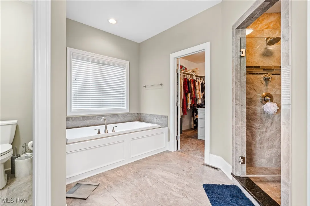 Full bathroom with a stall shower, a garden tub, and a walk in closet