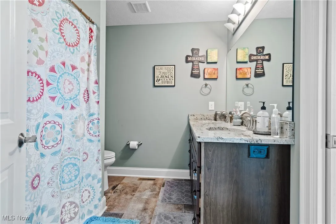 Full bath featuring vanity, stone finish flooring, and a shower with curtain