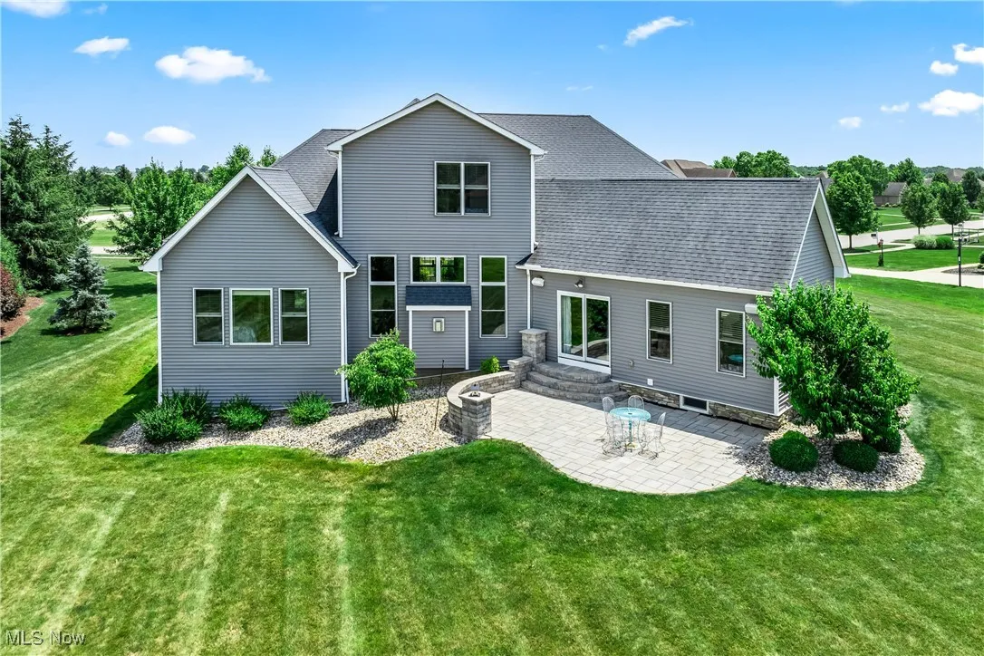 Rear view of property featuring a patio, a lawn, and roof with shingles