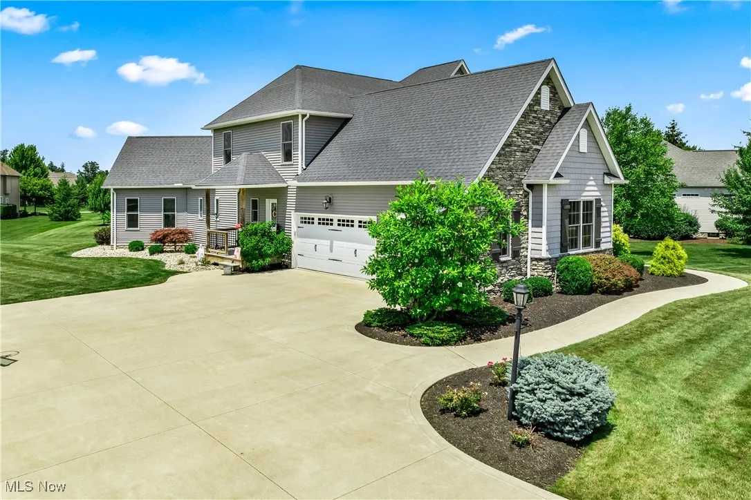 View of front facade with driveway, a front lawn, a shingled roof, and an attached garage