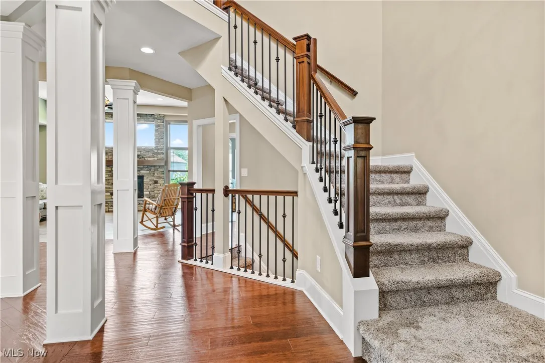 Stairs featuring decorative columns, wood finished floors, and recessed lighting