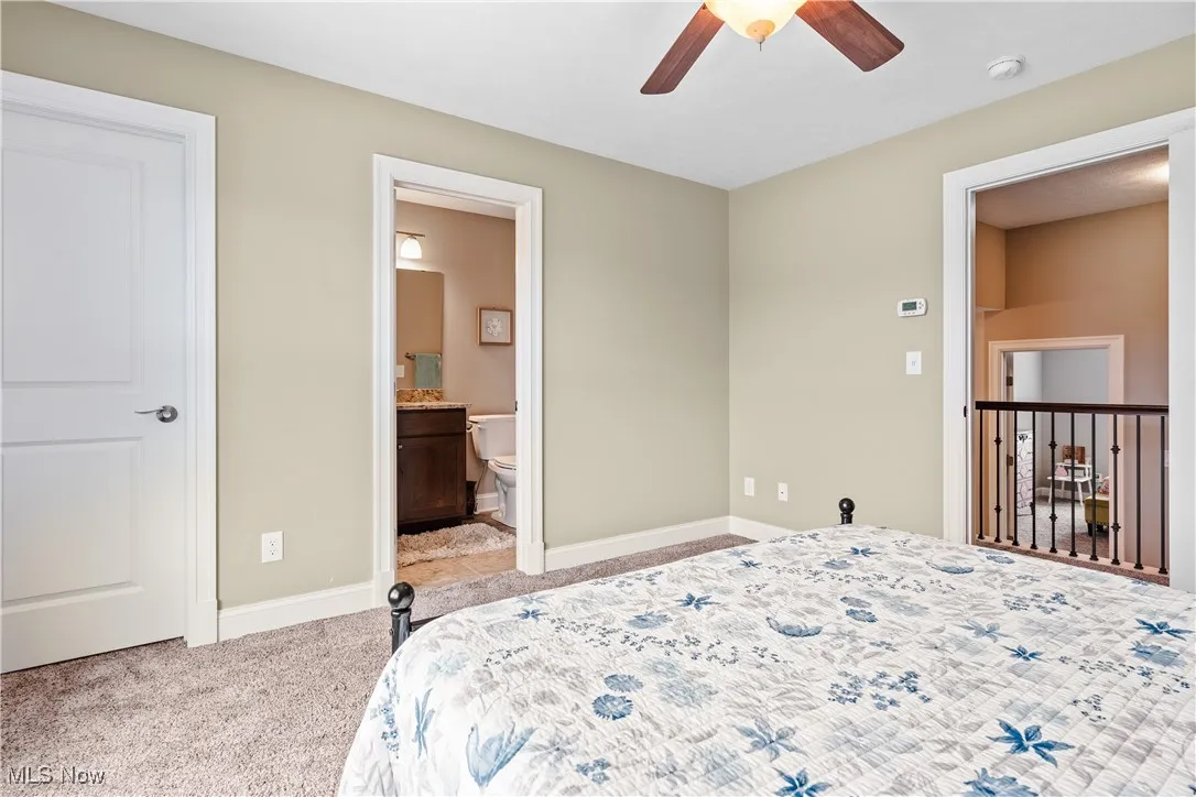 Bedroom featuring light carpet, connected bathroom, and a ceiling fan