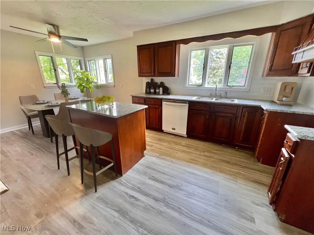 Kitchen featuring white dishwasher, tasteful backsplash, light wood-style floors, a center island, and a textured ceiling