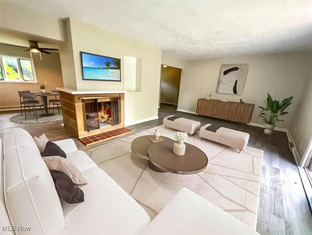 Living room featuring wood finished floors, a ceiling fan, and a tiled fireplace