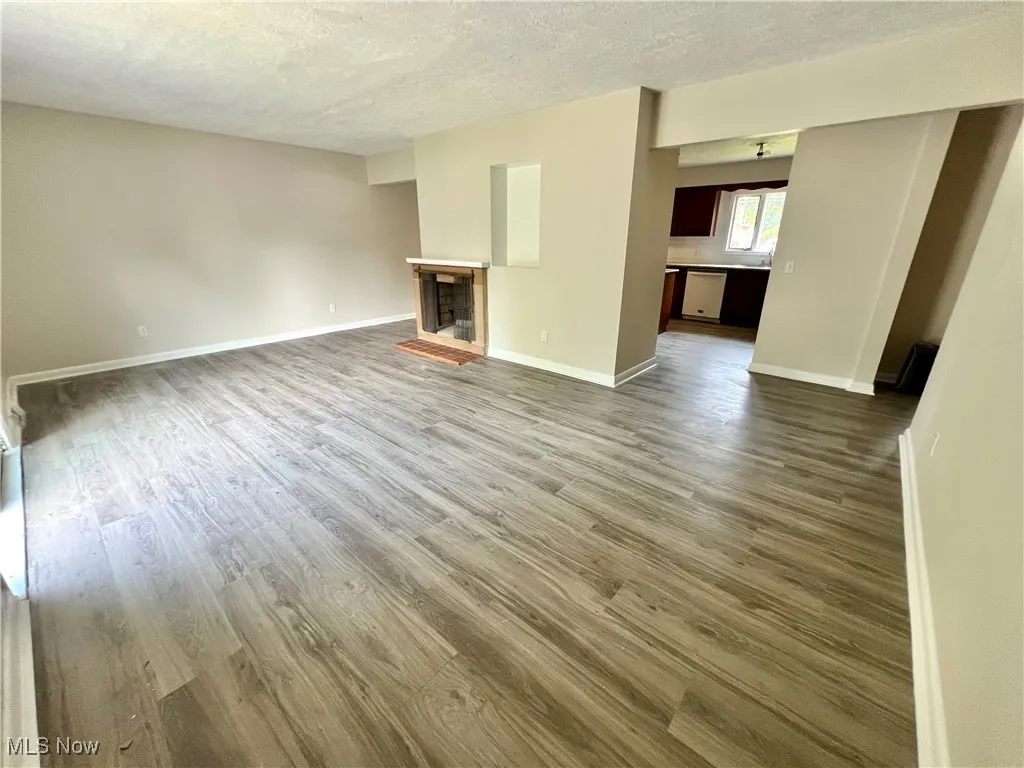 Unfurnished living room featuring dark wood-style floors, a textured ceiling, and a fireplace
