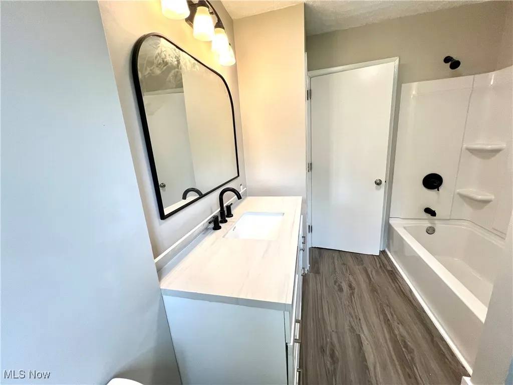 Bathroom featuring wood finished floors, vanity, and tub / shower combination