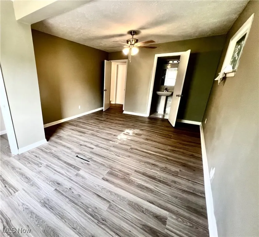 Unfurnished bedroom featuring wood finished floors, a textured ceiling, and a ceiling fan