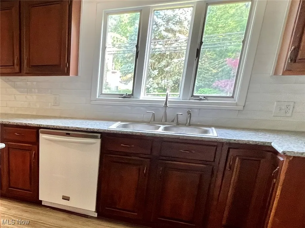 Kitchen with dishwasher, plenty of natural light, decorative backsplash, and light countertops