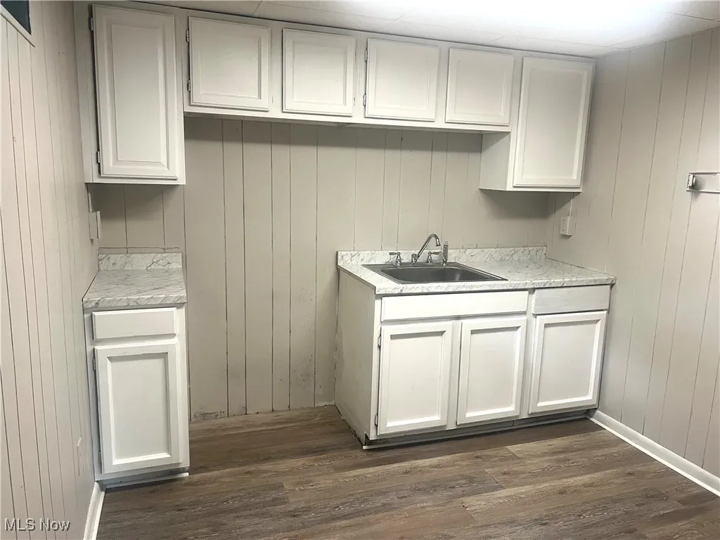 Kitchen featuring dark wood finished floors, light countertops, and wood walls