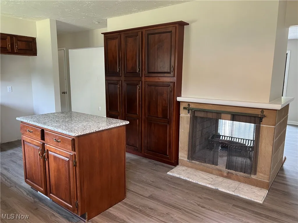 Kitchen with wood finished floors, a multi sided fireplace, a center island, and a textured ceiling